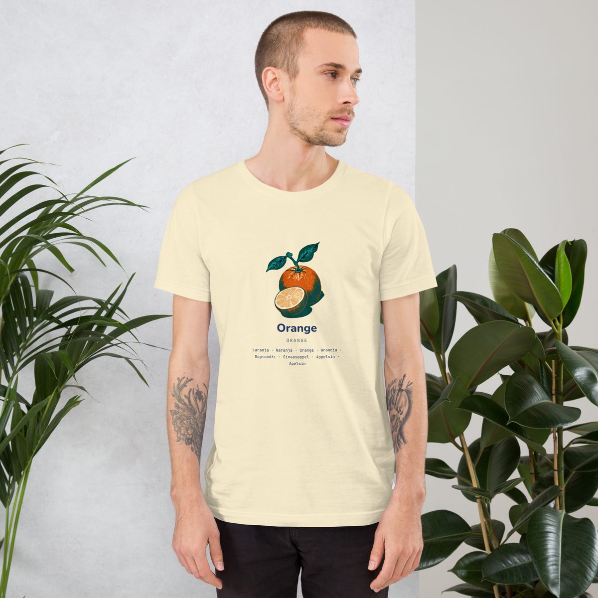 A man wearing the Laranja shirt, between two plants.